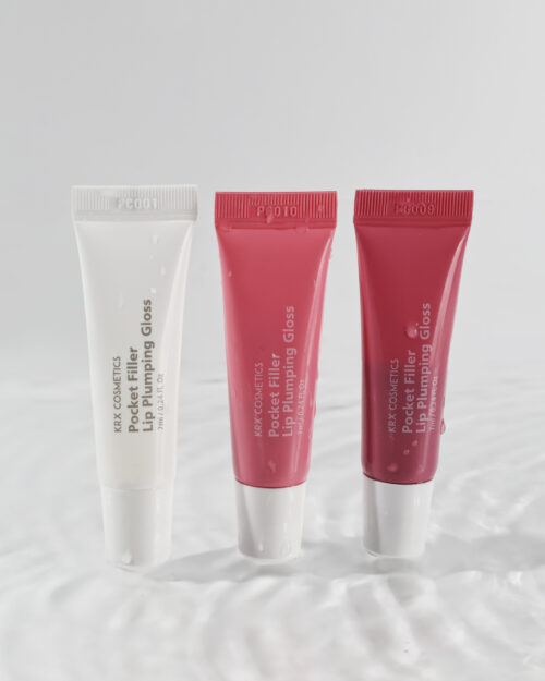 Drei Tuben KRX COSMETICS Pocket Filler Lip Plumping Gloss in den Farben Transparent, Rosé und Rot – auf glänzendem Hintergrund stehend.