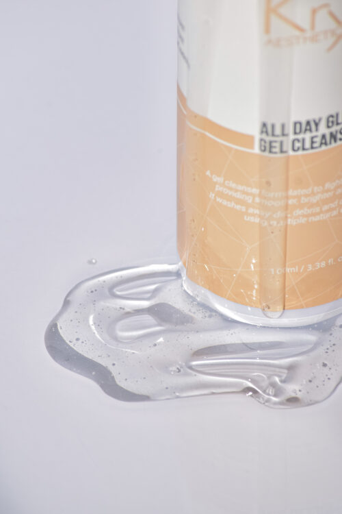 Nahaufnahme des KRX All Day Glow Gel Cleanser mit ausgelaufener Geltextur – Verpackung in weiß-goldenem Design.